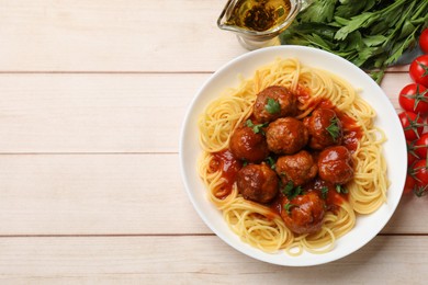 Delicious pasta with meatballs and ingredients on white wooden table, flat lay. Space for text