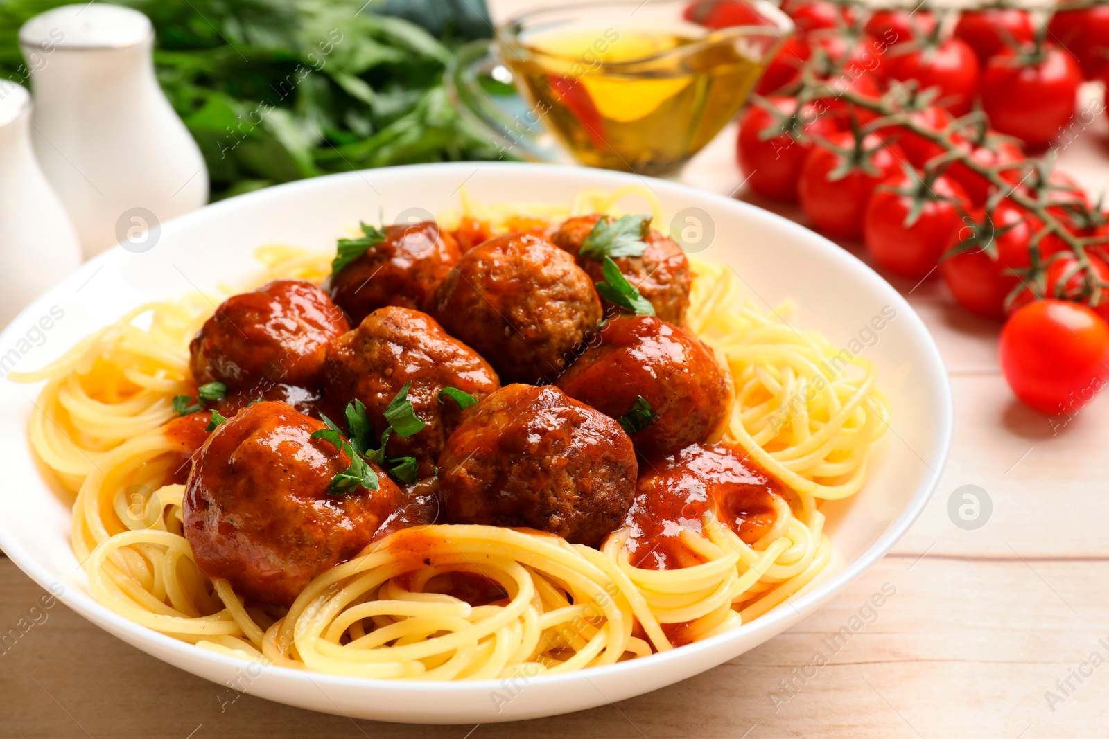 Photo of Delicious pasta with meatballs and ingredients on white wooden table, closeup