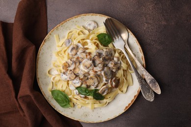 Photo of Delicious pasta with mushrooms and basil served on brown table, top view