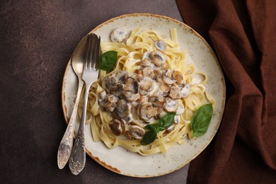 Photo of Delicious pasta with mushrooms and basil served on brown table, top view