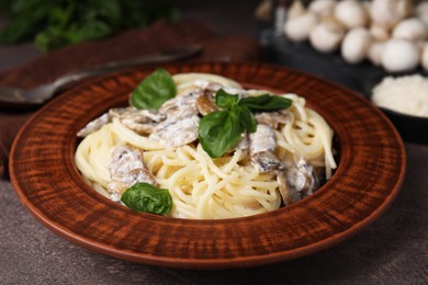 Photo of Delicious pasta with mushrooms and basil on brown table, closeup