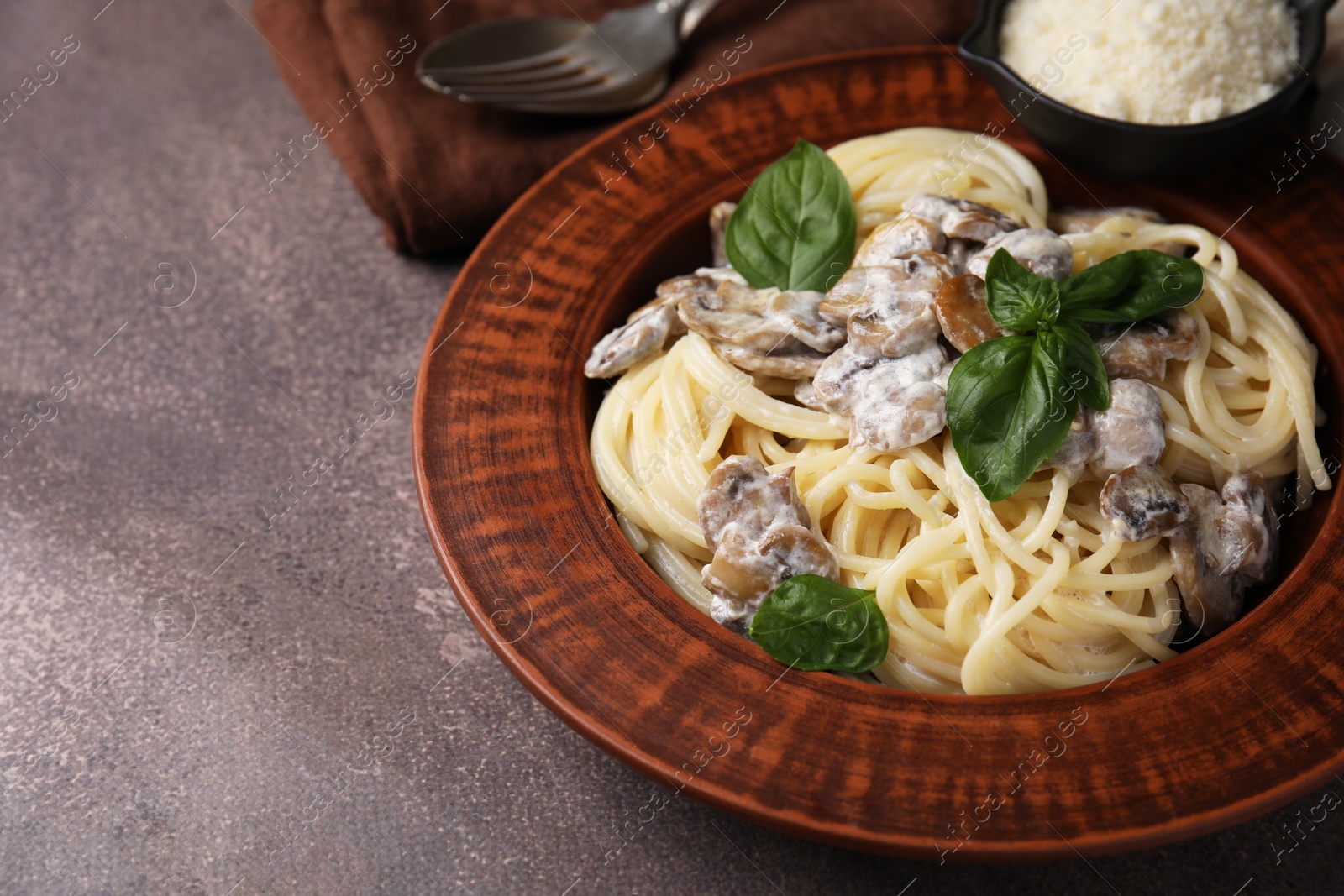 Photo of Delicious pasta with mushrooms and basil on brown table, closeup. Space for text