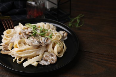 Photo of Delicious pasta with mushrooms on wooden table, closeup. Space for text