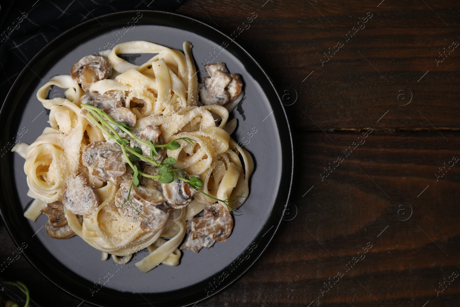 Photo of Delicious pasta with mushrooms on wooden table, top view. Space for text