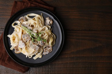 Photo of Delicious pasta with mushrooms on wooden table, top view. Space for text