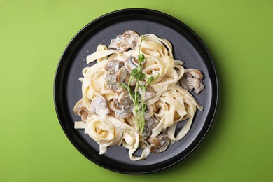 Photo of Delicious pasta with mushrooms on light green background, top view