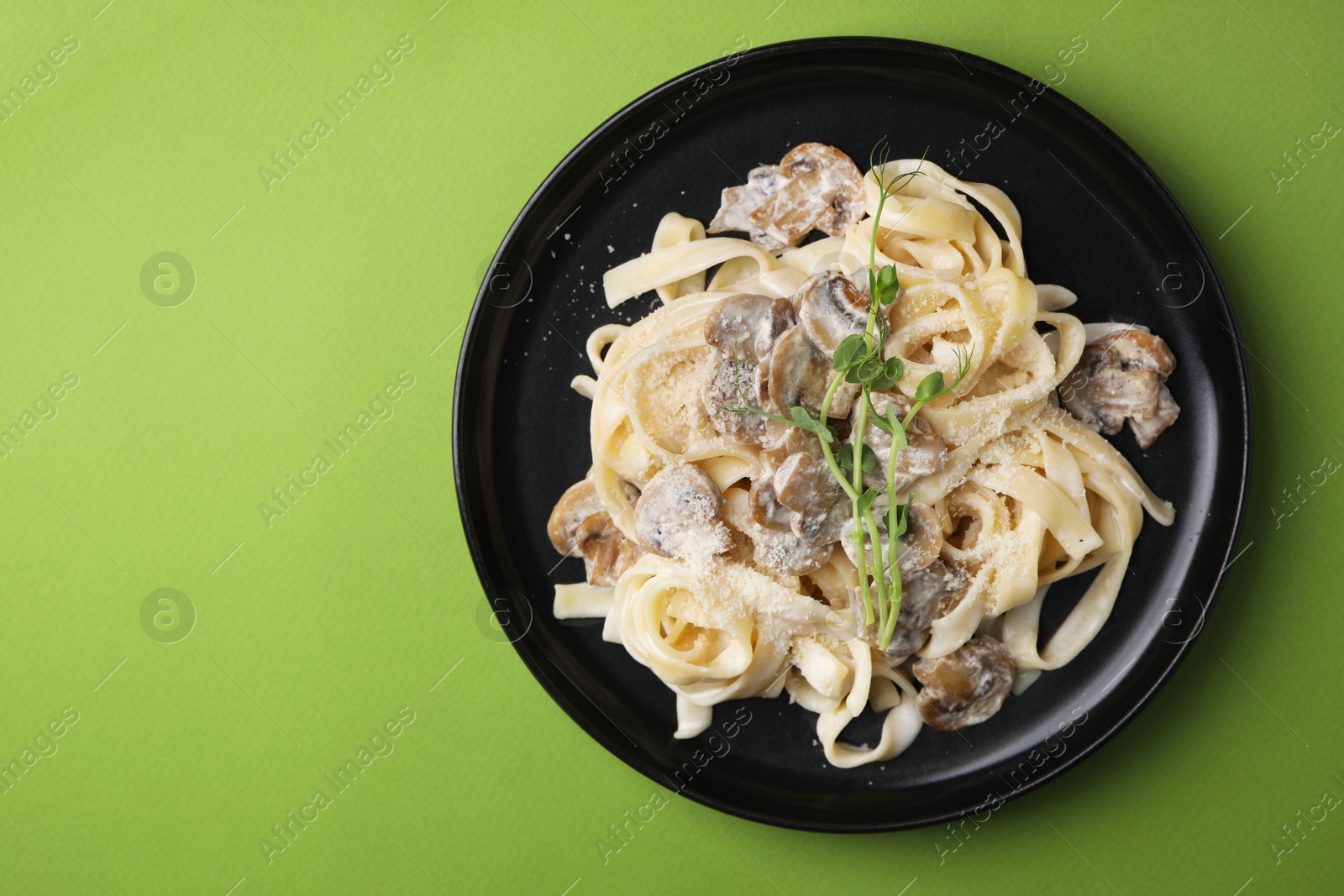 Photo of Delicious pasta with mushrooms on light green background, top view. Space for text