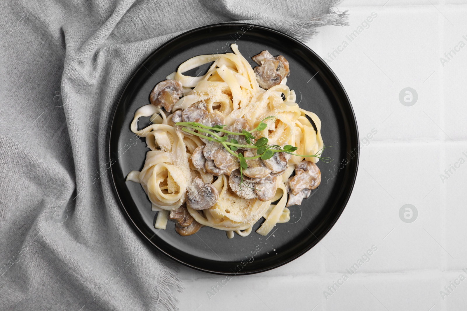 Photo of Delicious pasta with mushrooms on white tiled table, top view