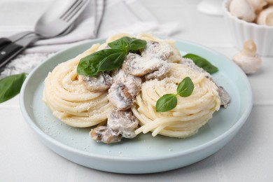 Photo of Delicious pasta with mushrooms and basil on white tiled table, closeup