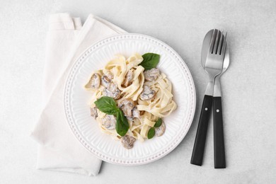 Photo of Delicious pasta with mushrooms and basil served on light table, flat lay