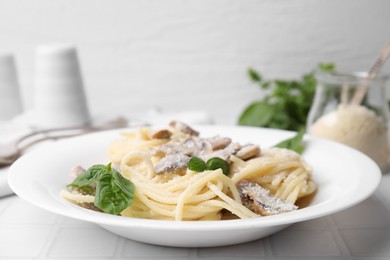 Photo of Delicious pasta with mushrooms and basil on white tiled table, closeup