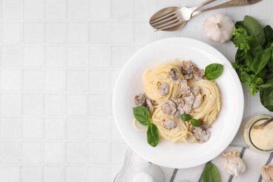 Photo of Delicious pasta with mushrooms and basil served on white tiled table, flat lay. Space for text