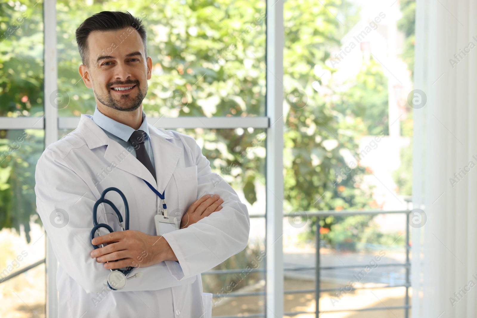 Photo of Smiling doctor with stethoscope indoors, space for text