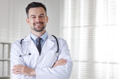 Smiling doctor with stethoscope in clinic, space for text