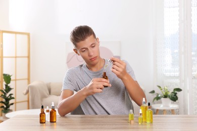 Young man dripping CBD tincture into bottle from dropper at wooden table