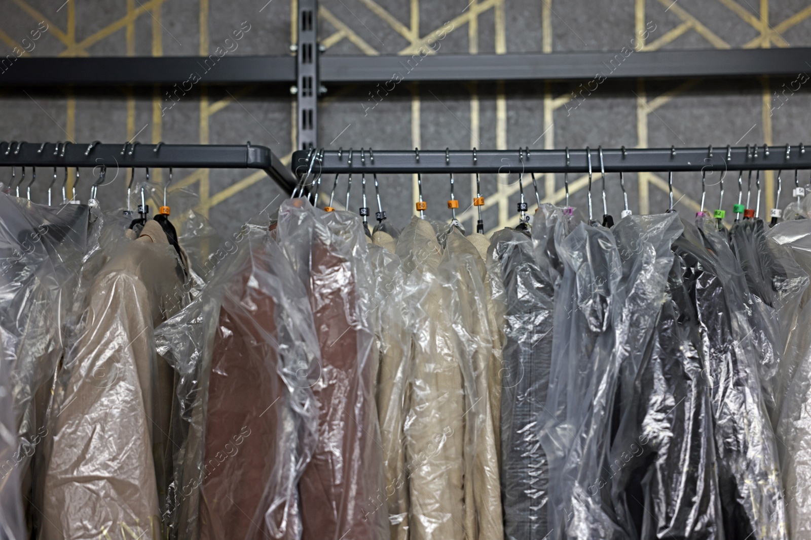 Photo of Many different clothes hanging from rack in professional workshop, closeup