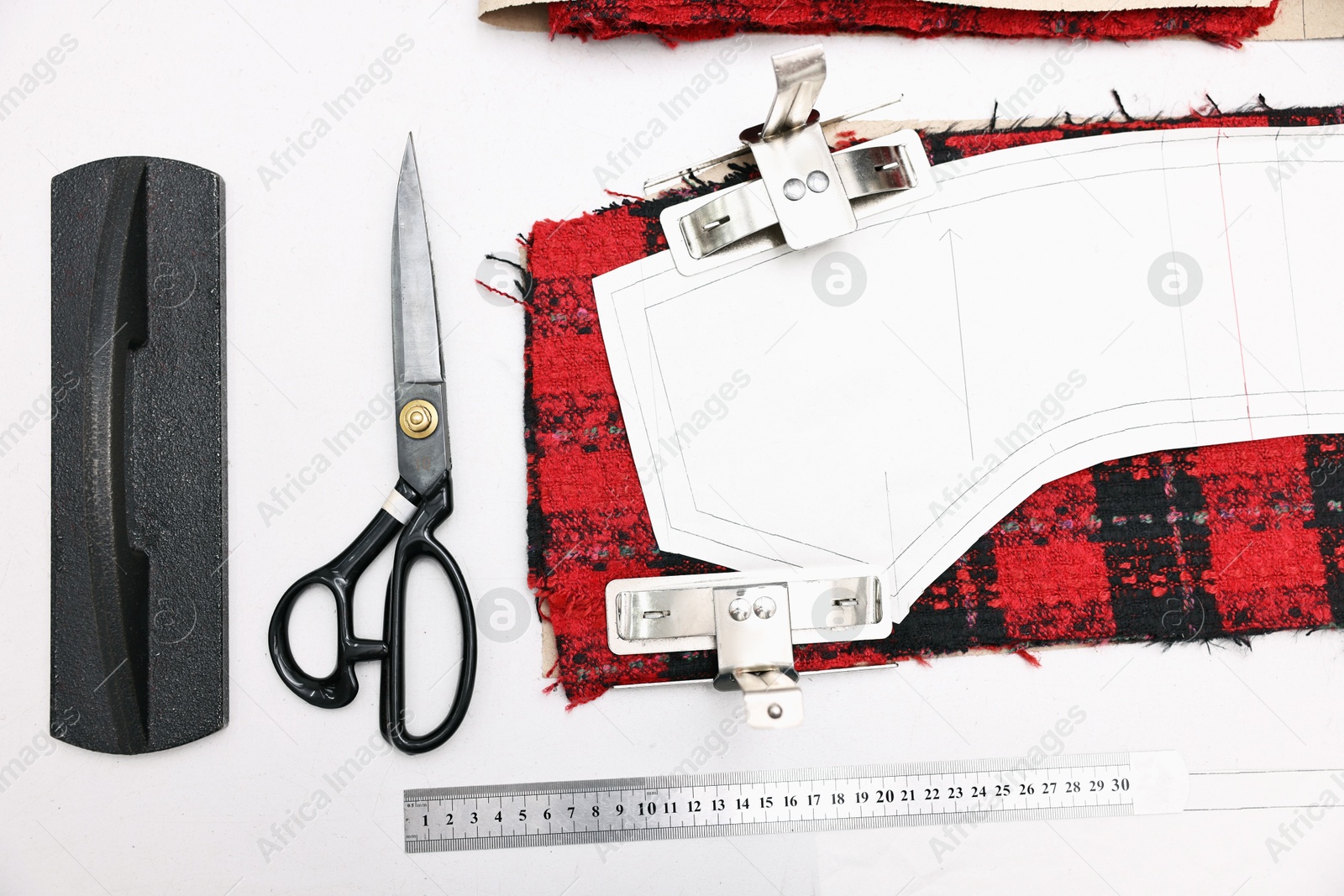 Photo of Pieces of fabric, measurements, scissors and other tools on white table