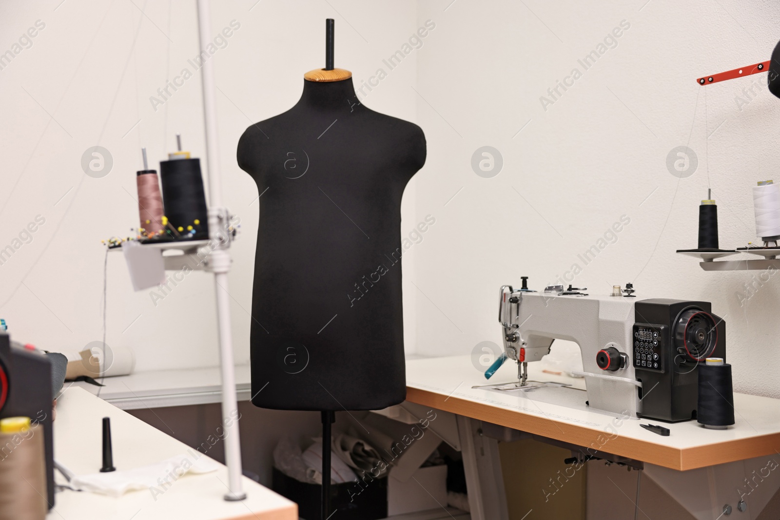 Photo of Professional workshop with sewing machine, table and mannequin