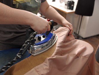 Young woman with iron working in professional workshop, closeup