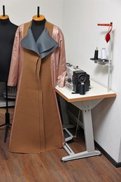 Photo of Professional workshop with sewing machine, table, coat and mannequin