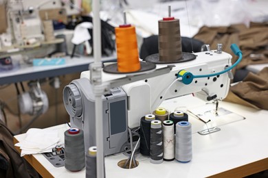 Photo of Sewing machines with spools of thread in professional workshop