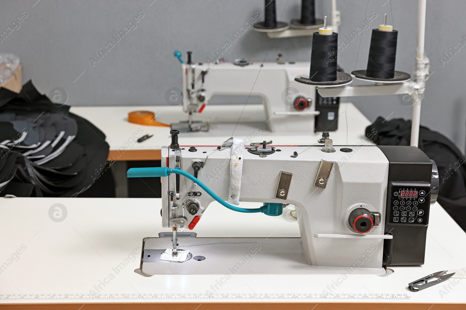 Photo of Sewing machines with spools of thread in professional workshop