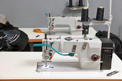 Photo of Sewing machines with spools of thread in professional workshop