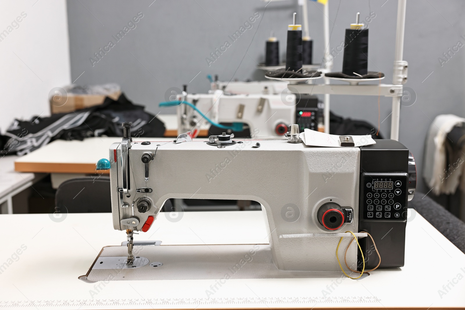 Photo of Sewing machines with spools of thread in professional workshop