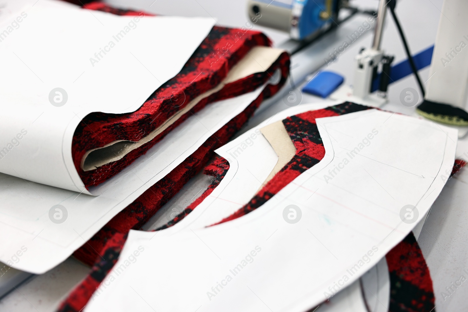 Photo of Pieces of fabric and measurements on white table in professional workshop, closeup