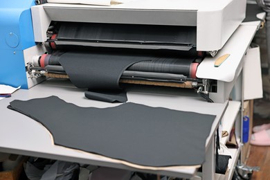 Photo of Machine and fabric on white table in professional workshop