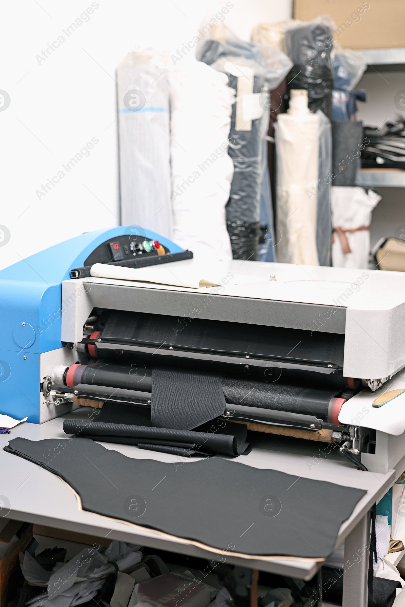 Photo of Machine and fabric on white table in professional workshop