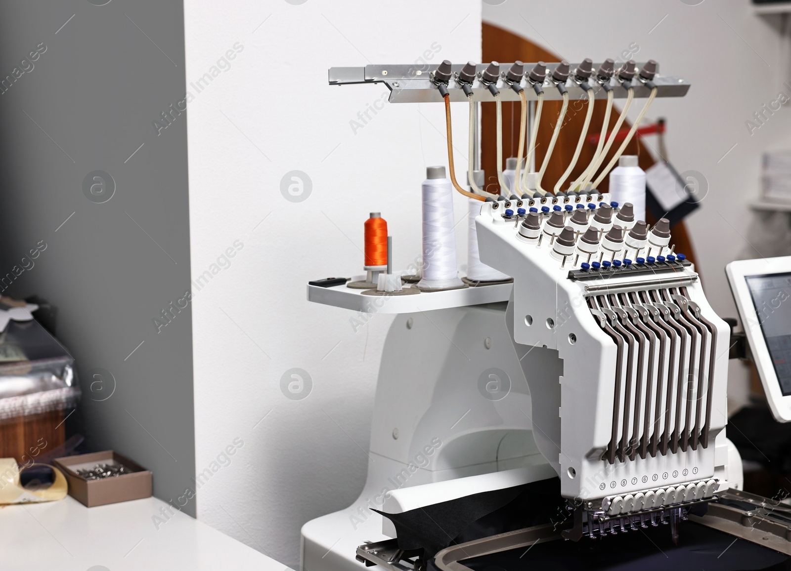 Photo of Sewing machine with spools of thread in professional workshop