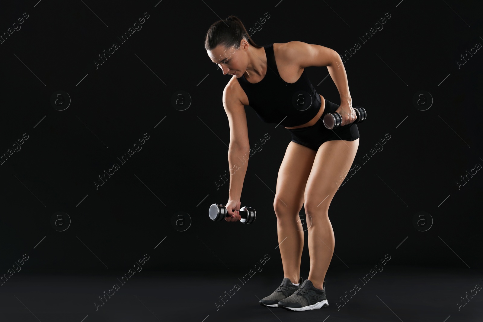 Photo of Woman exercising with dumbbells on black background, space for text