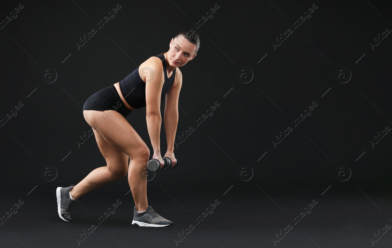 Photo of Woman exercising with dumbbells on black background, space for text