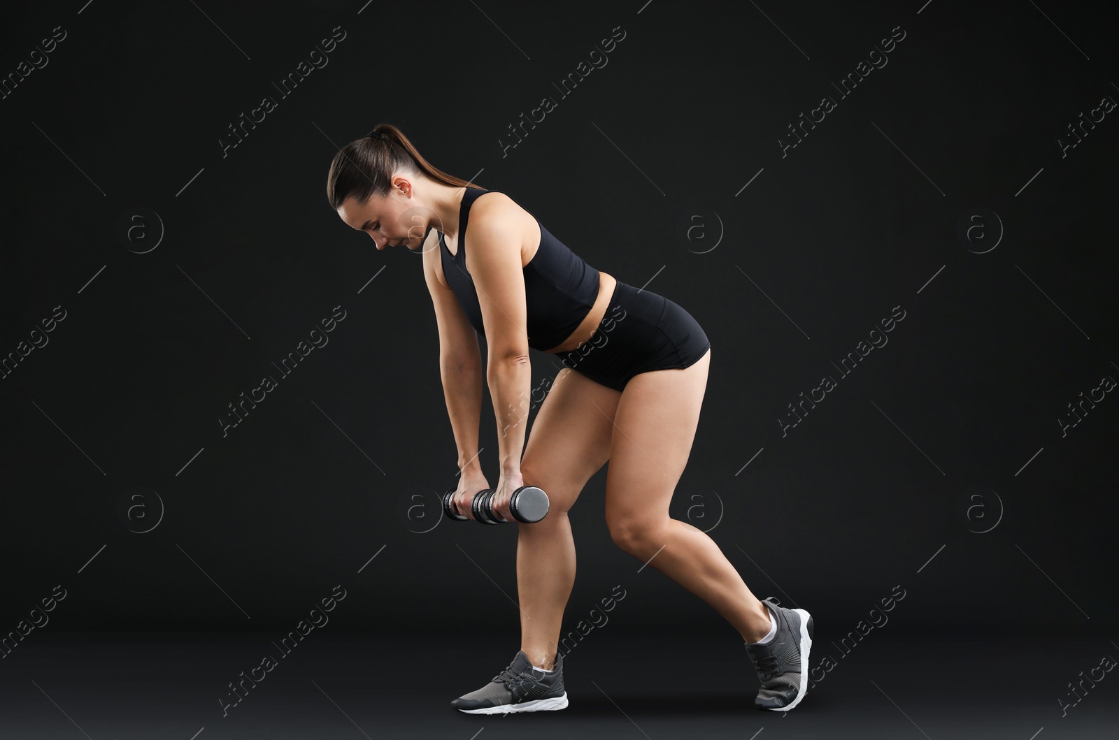 Photo of Woman exercising with dumbbells on black background