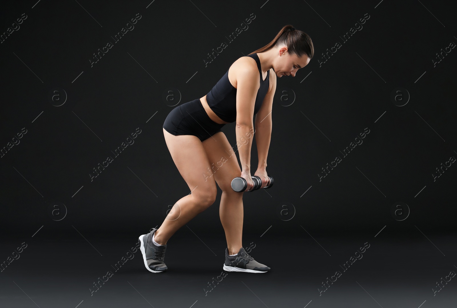 Photo of Woman exercising with dumbbells on black background