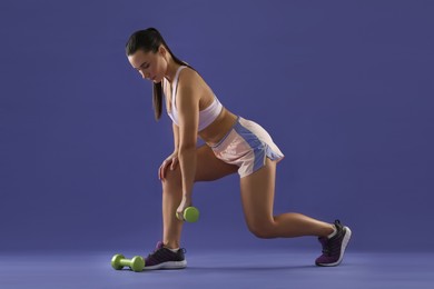 Photo of Woman exercising with dumbbells on purple background