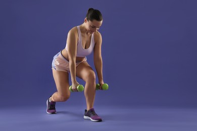 Photo of Woman exercising with dumbbells on purple background, space for text