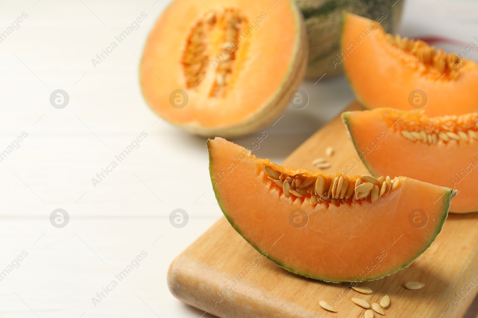 Photo of Cut ripe Cantaloupe melon on white table, closeup. Space for text