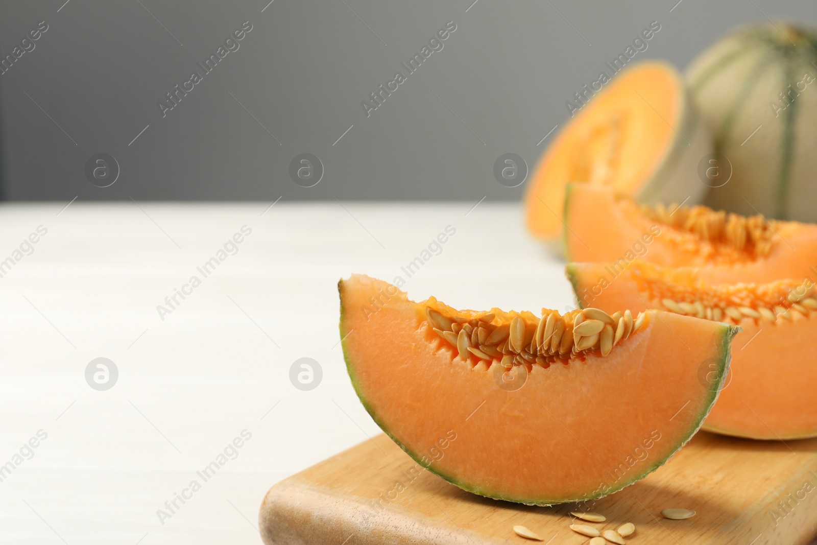 Photo of Cut ripe Cantaloupe melon on white table, closeup. Space for text