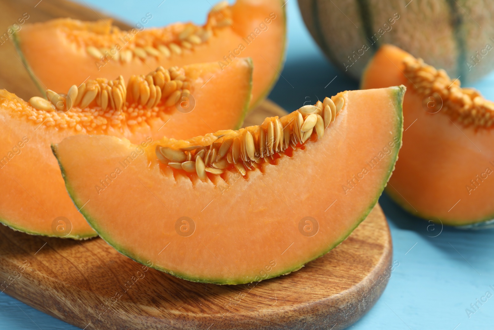 Photo of Tasty ripe Cantaloupe melon on light blue table, closeup