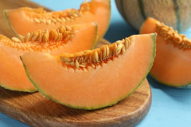 Photo of Tasty ripe Cantaloupe melon on light blue table, closeup