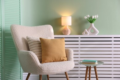 Photo of Two soft pillows on light armchair in living room