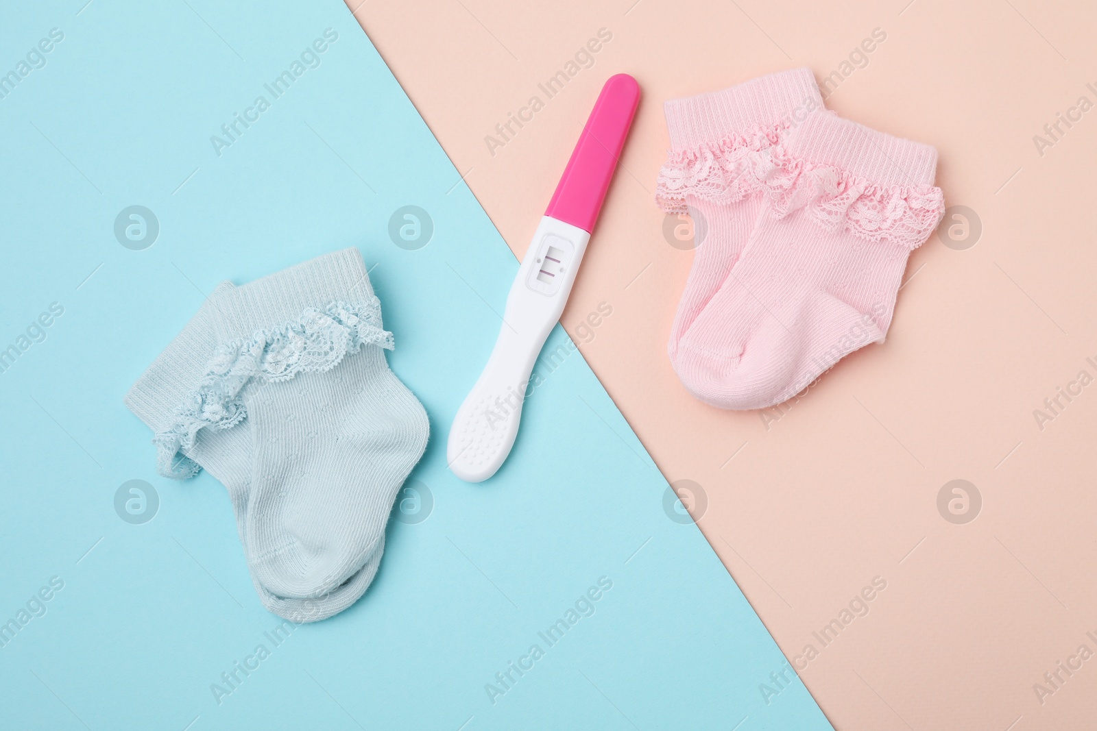 Photo of Pregnancy test and baby socks on color background, flat lay