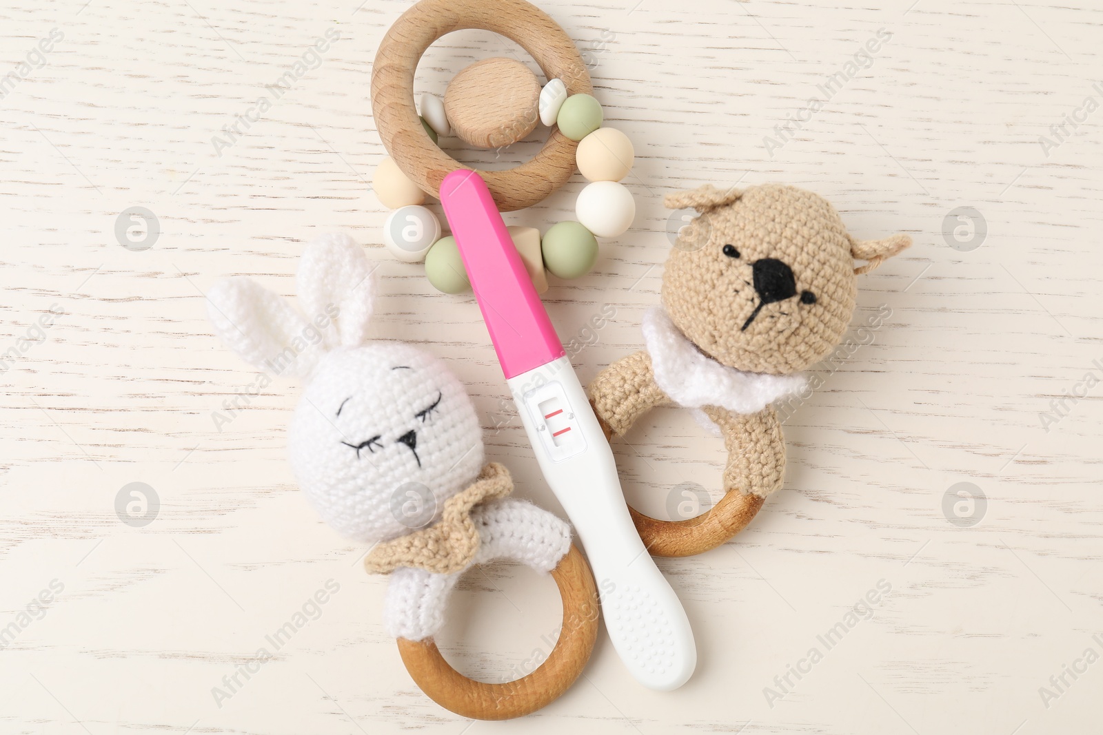 Photo of Pregnancy test and baby toys on white wooden table, flat lay