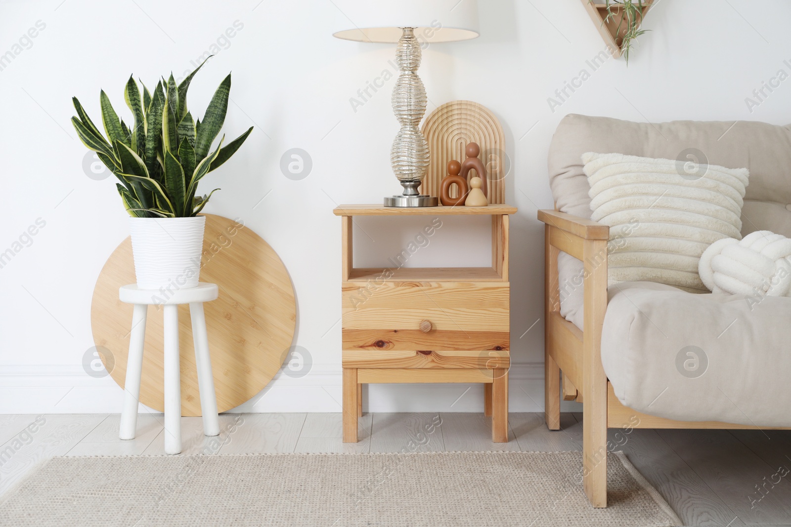 Photo of Stool, sofa, lamp and houseplant at home. Interior design