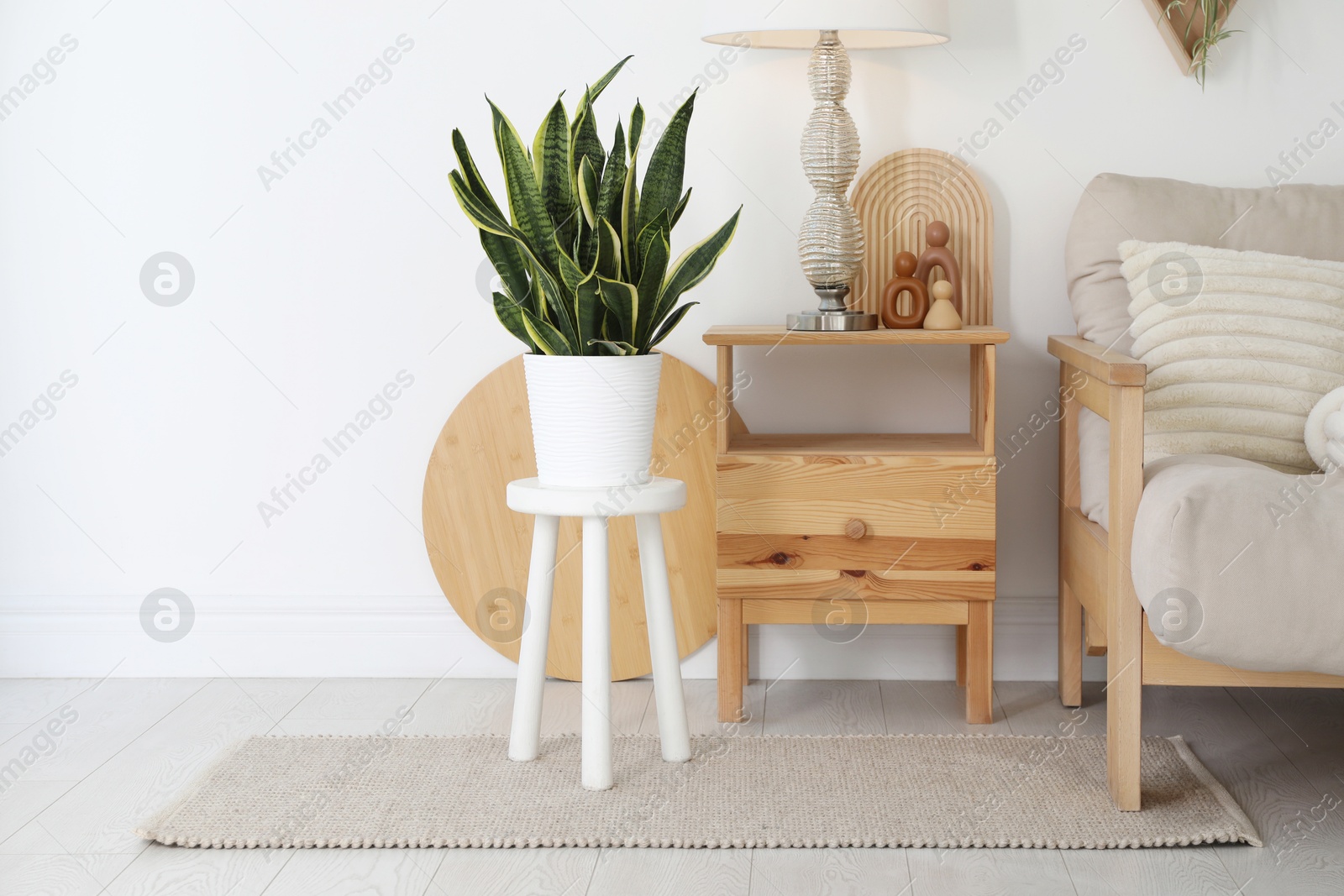 Photo of Stool, sofa, lamp and houseplant in room. Interior design