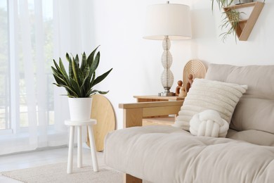 Photo of Stool, sofa, lamp and houseplant at home. Interior design