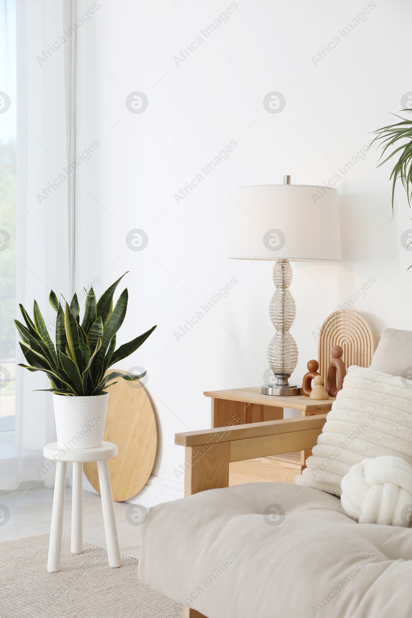 Photo of Stool, sofa, lamp and houseplant at home. Interior design