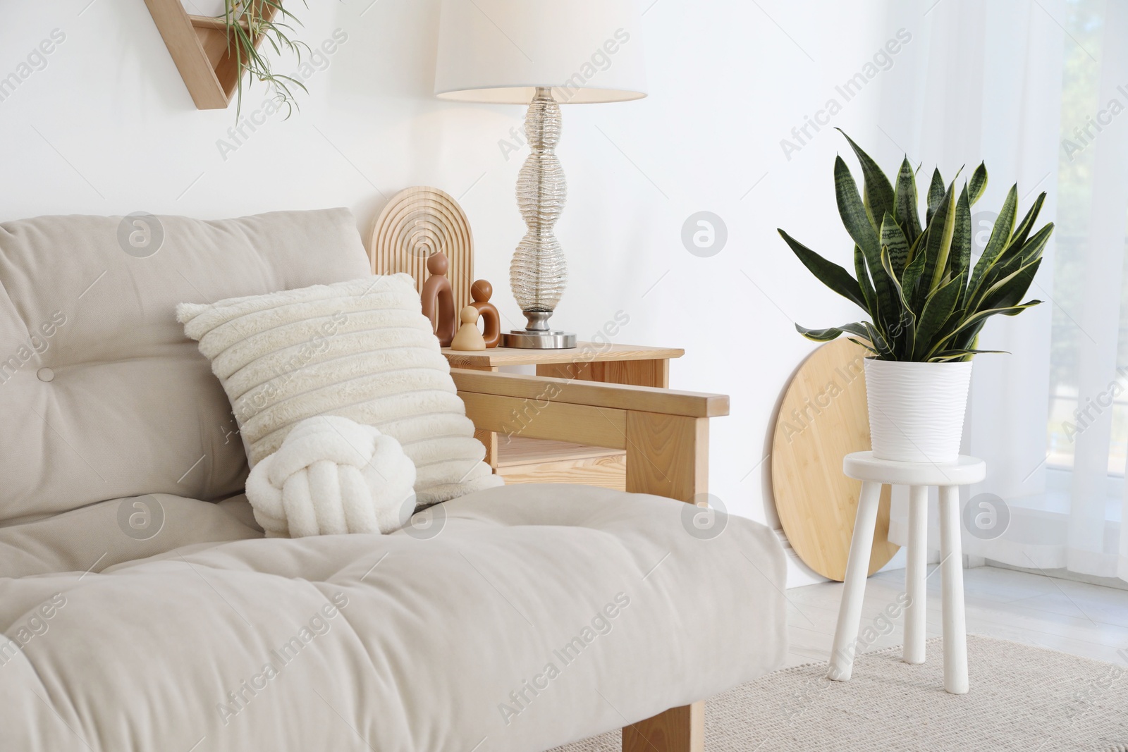 Photo of Stool, sofa, lamp and houseplant at home. Interior design